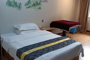 A neatly made bed with a white and blue bedspread, a wooden nightstand with a red cloth, and a wall with a green landscape painting. - TingTaoJu Hotel (Zhuhai)
