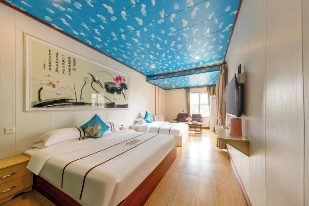 A hotel room with a large bed, a desk, a TV, and a ceiling with a blue pattern.