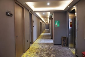 A hotel hallway with doors, a carpeted floor, and an elevator.