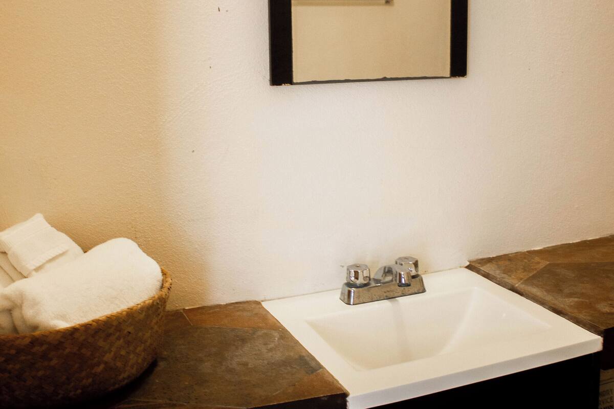 Une salle de bain avec un lavabo blanc, un miroir et un panier rempli de serviettes.
