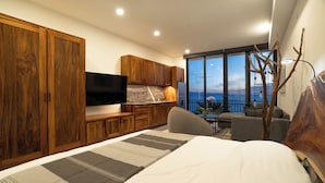 A modern bedroom with a large bed, wooden wardrobe, flat-screen TV, and a balcony with a view. - La Ventana Beach Resort (La Ventana)