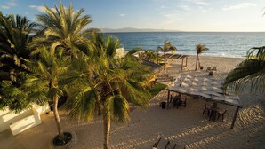 A beachside resort with palm trees, a shaded seating area, and a view of the ocean. - La Ventana Beach Resort (La Ventana)
