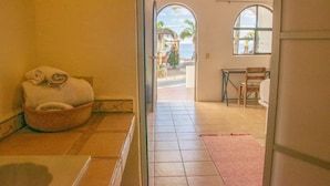 A room with a bed, a small table, and a chair. There is a window with a view of palm trees and a beach. - La Ventana Beach Resort (La Ventana)