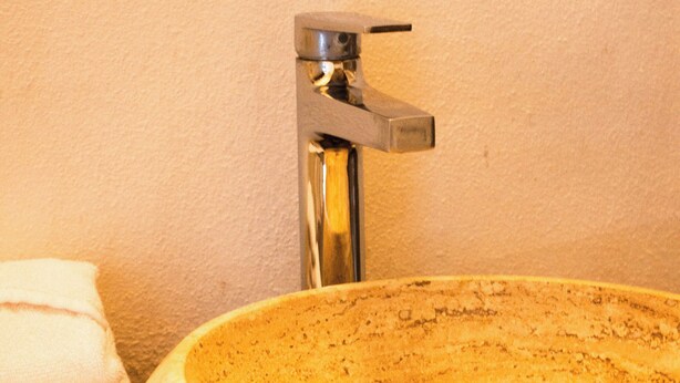 A bathroom with a round stone sink, a towel, and a chrome faucet. - La Ventana Beach Resort (La Ventana)