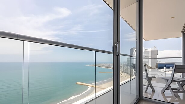A balcony with a glass railing overlooking a beach and the sea. - Awesome Sea View and Historic Center “Morros City” (Cartagena de Indias)