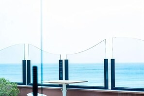 A table and chairs by a window with a view of the sea. - Dreamer Boutique Hotel (Pingtung)