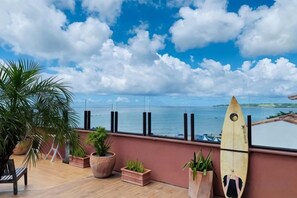 A balcony with a view of the sea, potted plants, and a surfboard. - Dreamer Boutique Hotel (Pingtung)