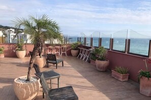 A terrace with outdoor seating, potted plants, and a view of the sea. - Dreamer Boutique Hotel (Pingtung)