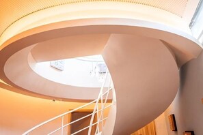 Una scala a chiocciola dal design moderno che conduce a un livello superiore illuminato da luce naturale.