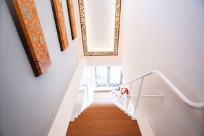 Een trap met een witte leuning, houten treden en decoratieve wandversieringen.