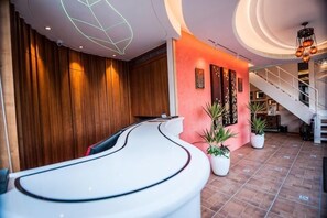 A reception area with a curved reception desk, wooden paneling, potted plants, and a staircase leading to an upper level. - Dreamer Boutique Hotel (Pingtung)