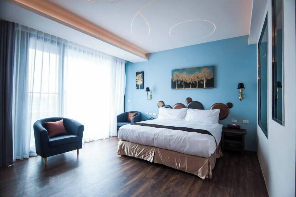 Et soveværelse med seng, stol, natbord og et maleri på væggen.
