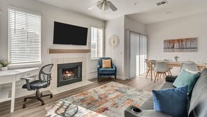 A modern living room with a fireplace, a dining area, and a TV mounted on the wall. - Remodeled Apt Pool Gym - Near Hill AFB Lagoon (Clearfield)