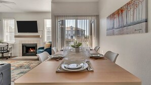 A dining area with a long table set for six, a fireplace, and a large window with blinds. - Remodeled Apt Pool Gym - Near Hill AFB Lagoon (Clearfield)