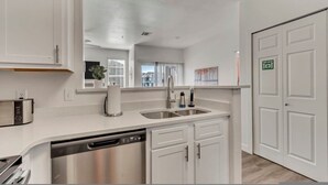 A modern kitchen with white cabinetry, stainless steel appliances, and a double sink. - Remodeled Apt Pool Gym - Near Hill AFB Lagoon (Clearfield)