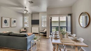 Un salon moderne avec un canapé, une table à manger pour quatre personnes et un ventilateur de plafond.