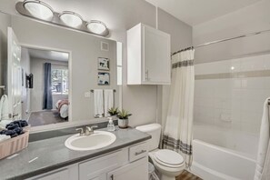 A bathroom with a double sink vanity, a toilet, a bathtub, and a shower curtain. - L189 at Mountain View by CDH (Clearfield)