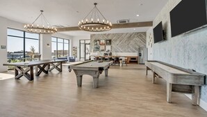 Una habitación amplia con mesa de billar, una larga mesa de comedor y una zona de bar.