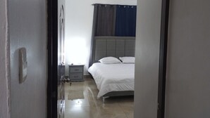 Een slaapkamer met een bed, nachtkastje en gordijn.