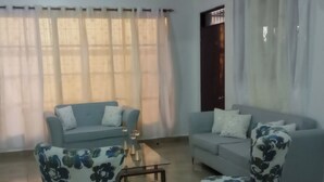 Een woonkamer met twee banken, een bijzettafeltje en fauteuils met een bloemenprint.