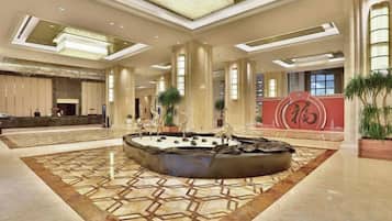 A spacious lobby with a central fountain, a reception desk, and a large decorative wall with Chinese characters.