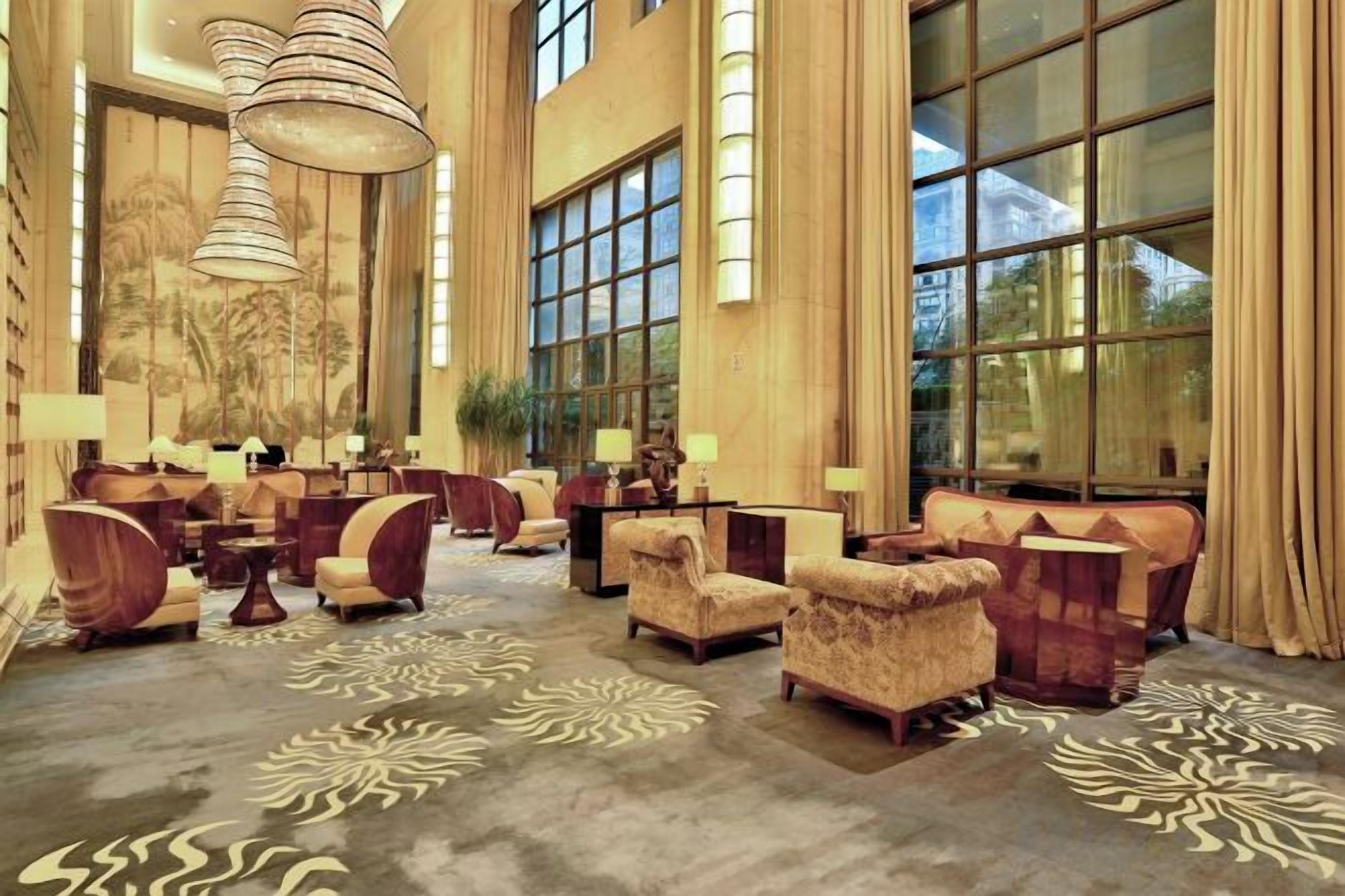 A spacious lobby with multiple seating areas, large windows, and a chandelier.