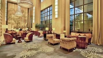 A spacious lobby with multiple seating areas, large windows, and a chandelier.