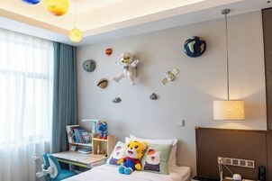 Habitación de hotel con cama, escritorio y silla. Objetos decorativos en la pared, incluyendo un peluche y un globo terráqueo.