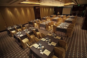 A conference room with round tables, chairs, and a projector screen. - Lanxi World Trade Hotel (Lanxi)
