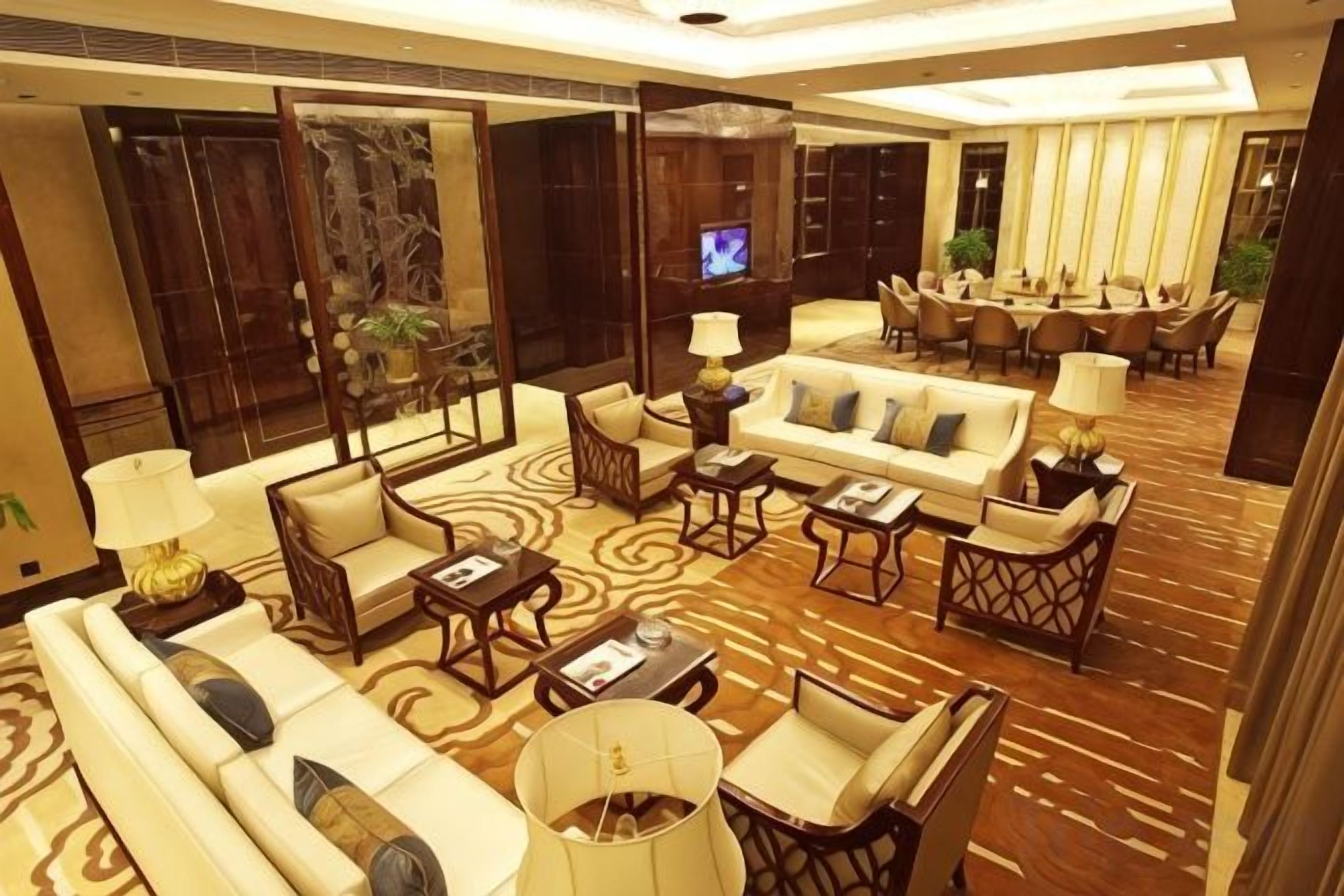 Un amplio vestíbulo de hotel con una gran zona de estar, un televisor y un comedor.