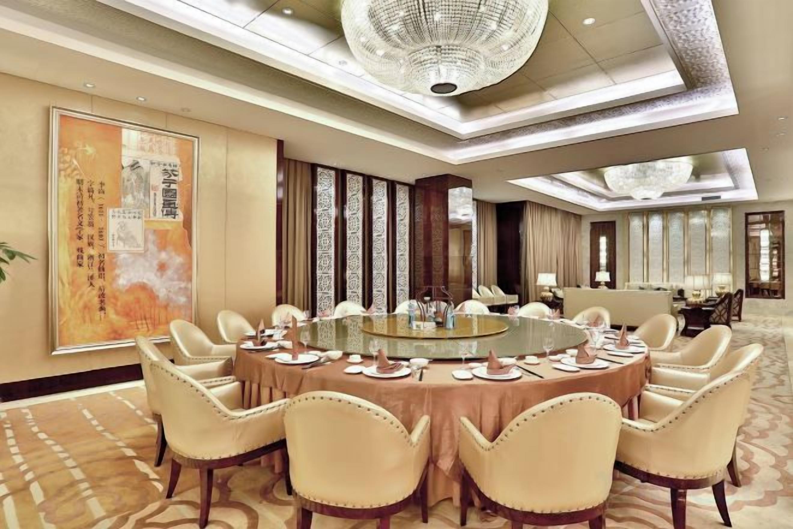 A conference room with a round table, chairs, and a chandelier.