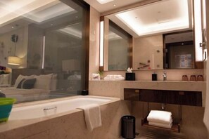 Une salle de bain moderne avec une grande baignoire, un miroir et un meuble-lavabo avec des articles de toilette.