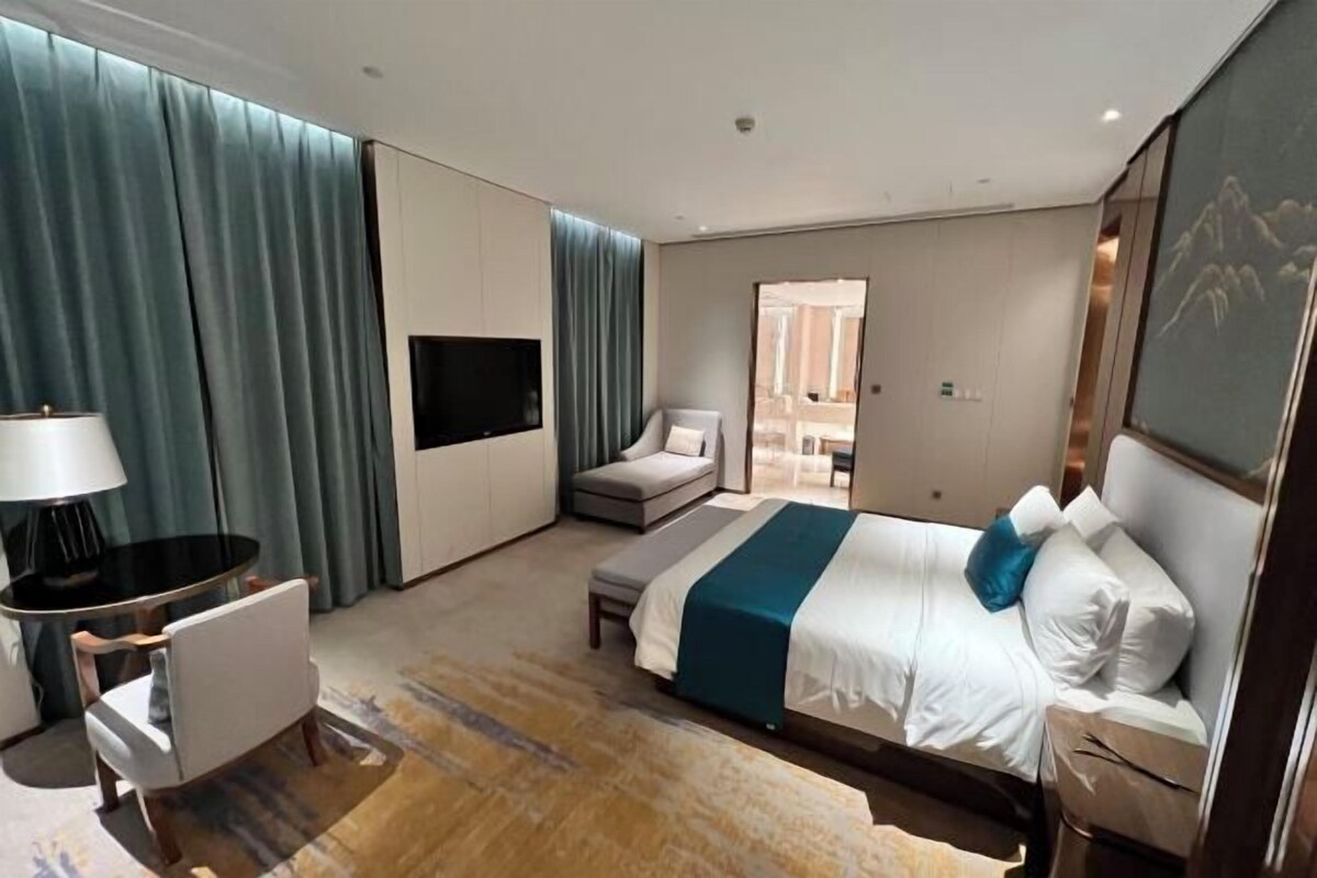 Une chambre d’hôtel moderne, dotée d’un grand lit, d’un bureau, d’une chaise et d’un téléviseur.