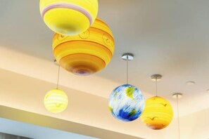 Un plafond orné de luminaires sphériques suspendus, dont certains représentent la Terre et d’autres arborent des motifs abstraits.