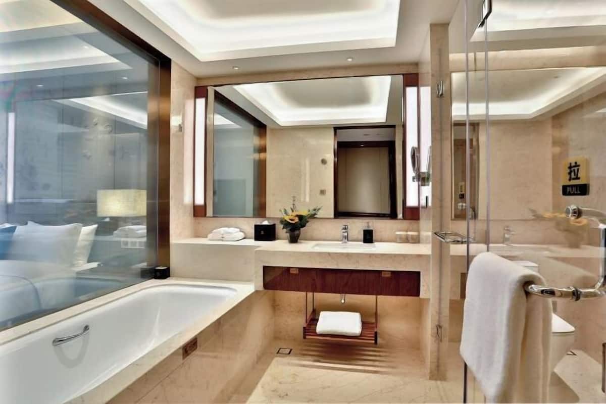 A modern bathroom with a large bathtub, dual sinks, a glass shower enclosure, and a vanity with a mirror.