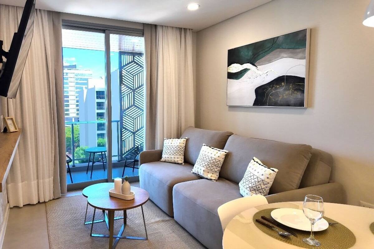 A modern living room with a sofa, a small round table, and a painting on the wall.