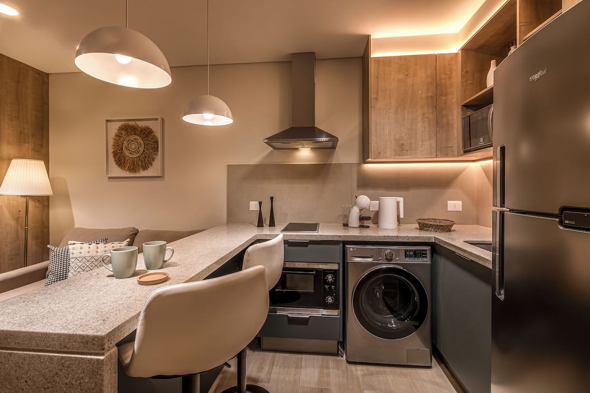 A modern kitchen with built-in appliances, a dining area with a table and chairs, and pendant lighting.