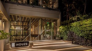 A modern building with a glass entrance, outdoor seating, and a sign reading "HOUSE". - Houze Residences – By AVA Rentals. (Asunción)