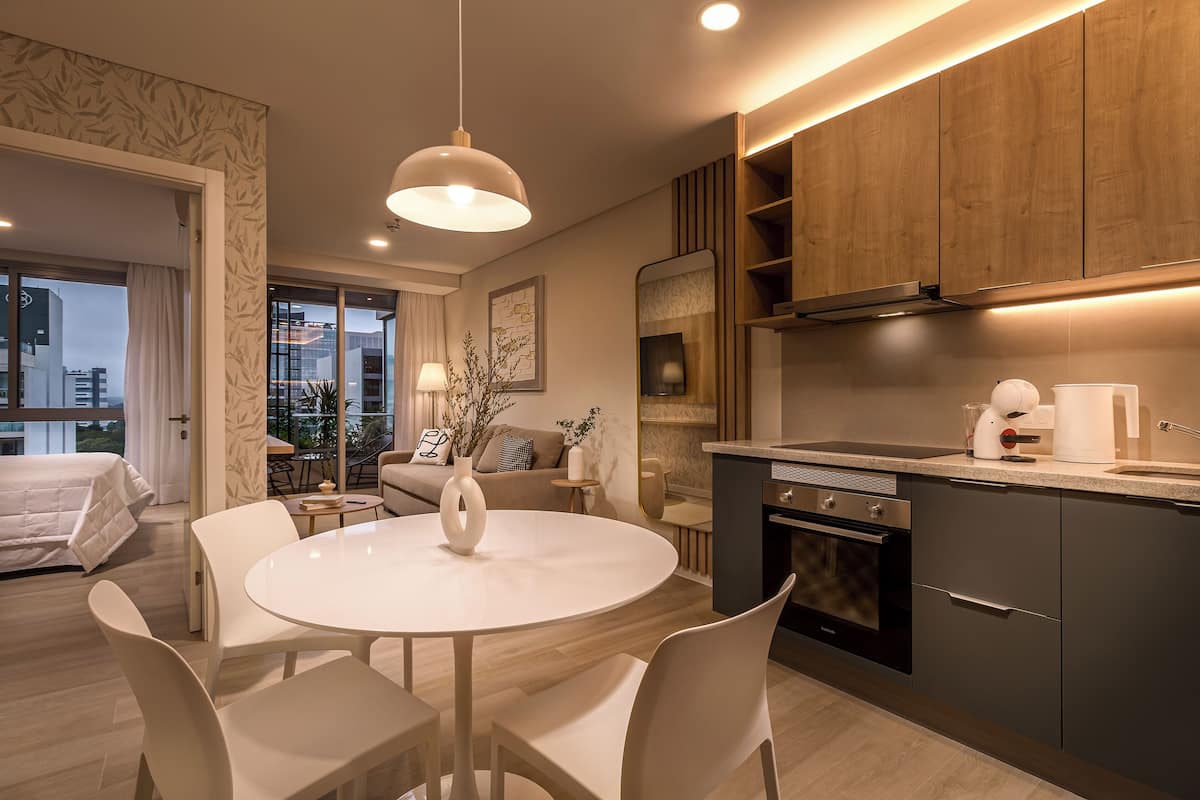 A modern hotel room with a dining area, a kitchen, and a living space.