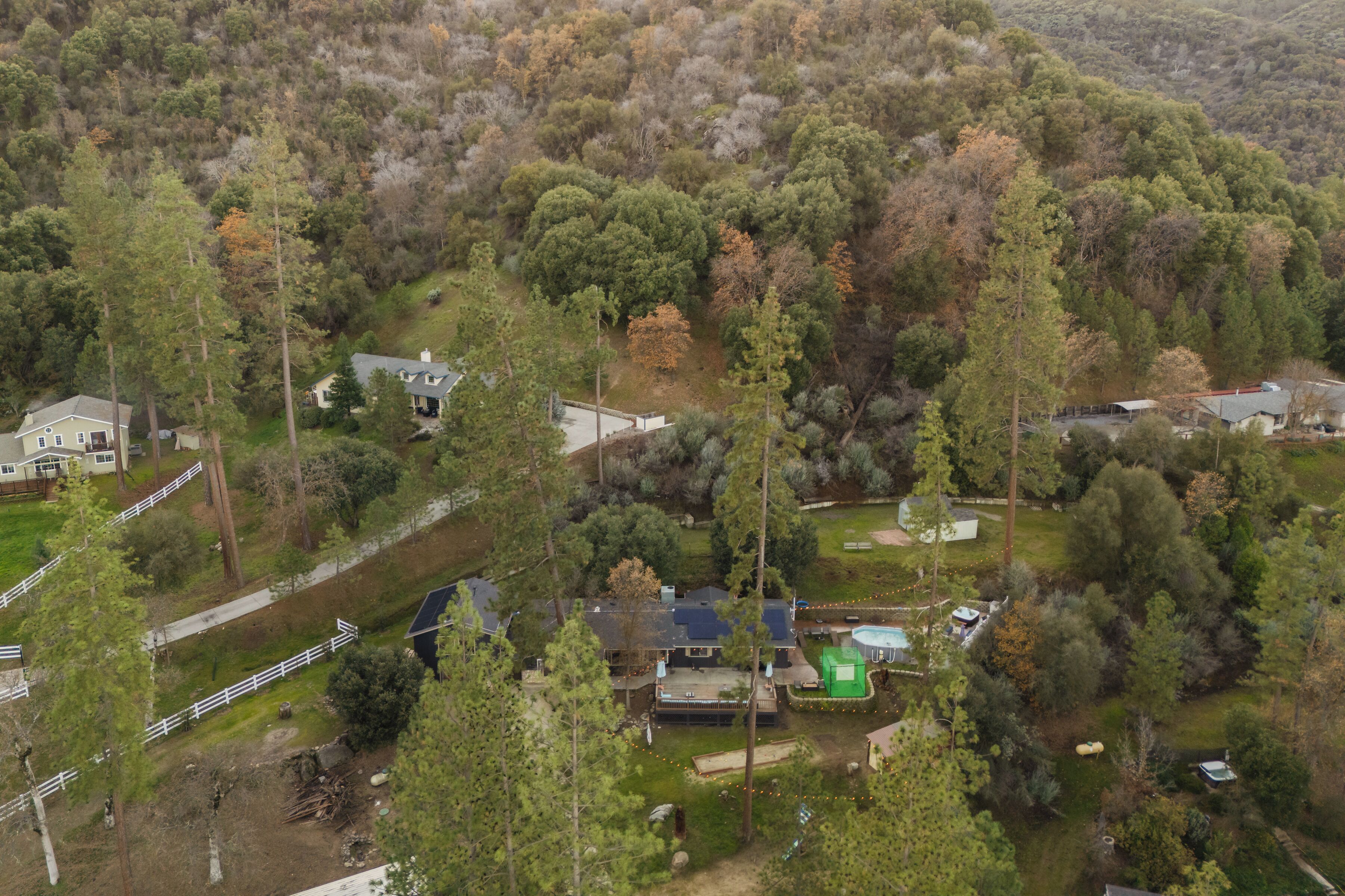 An aerial view of a residential area with houses surrounded by dense forest.
