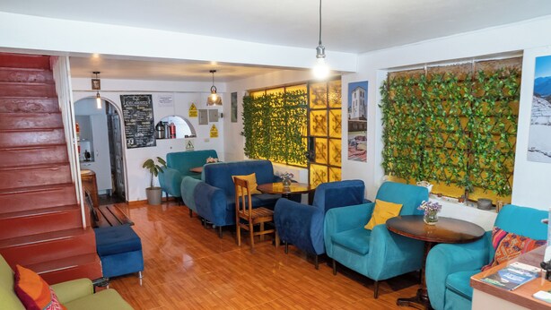 Una sala de estar moderna con una escalera, sillones azules, una mesa de centro de madera y una pared cubierta de plantas verdes.