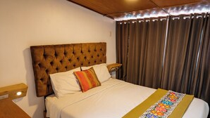 Una cama bien hecha con un cabecero capitonado, ropa de cama blanca y una colcha bordada de colores.