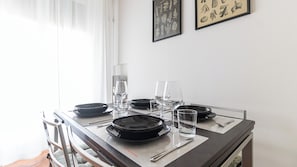 A dining table set with plates, glasses, and cutlery, with a chair visible to the left.