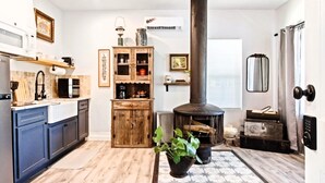 A kitchen with a wood-burning stove, blue cabinets, and a potted plant. - Rustic Studio Rain Shower 3min-asian Dist (Oklahoma City)