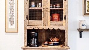 A rustic wooden cabinet with shelves containing kitchen items like a coffee maker, teapot, and jars. - Rustic Studio Rain Shower 3min-asian Dist (Oklahoma City)