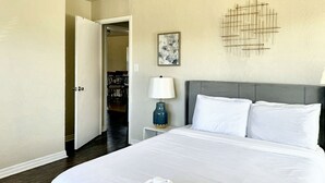 Ein Hotelzimmer mit einem großen Bett, weißen Bettwäsche, einer blauen Lampe und einem Bild an der Wand.