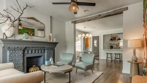 Una sala de estar con chimenea, un comedor y una cocina al fondo.
