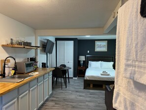 A compact hotel room with a kitchenette, a dining area, and a bed. - Cute Tiny House With Fenced Yard Near Plaza Dist (Oklahoma City)