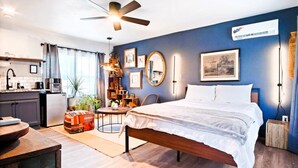 Ein modernes Schlafzimmer mit Bett, Schreibtisch und einer Küchenzeile.