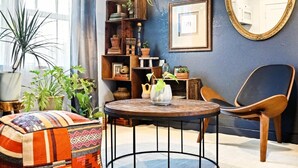 Ein gemütliches Wohnzimmer mit einem runden Holztisch, einem bequemen Sessel und einer Bücherwand voller Bücher und Dekoration.
